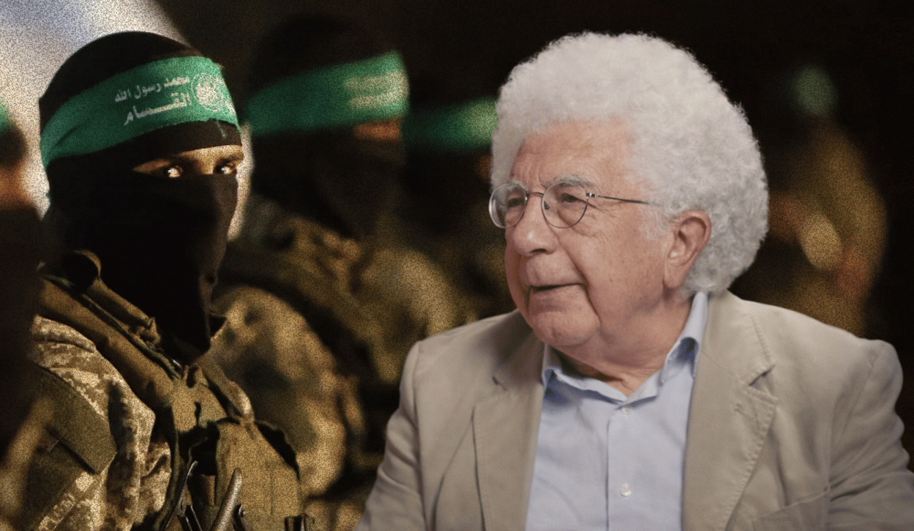 Avi Shlaim, an elderly man with white curly hair and glasses, sits in profile wearing a beige blazer, with a blurred background of masked men in military fatigues and green headbands.