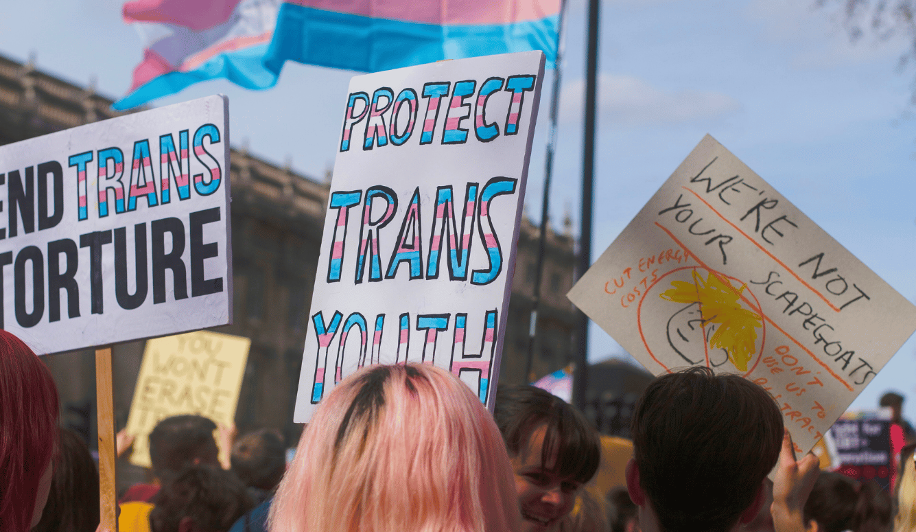 Protesters hold placards reading “Protect Trans Youth” and “End Trans Torture” at a transgender rights rally.