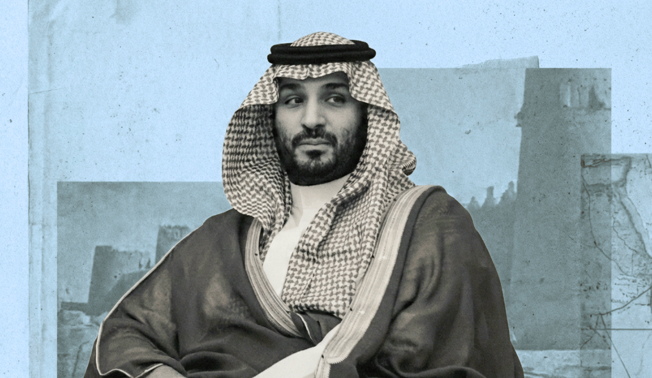 MBS in Saudi dress with a checked headscarf and dark robe, seated against a blue-toned backdrop with faint architectural shapes.