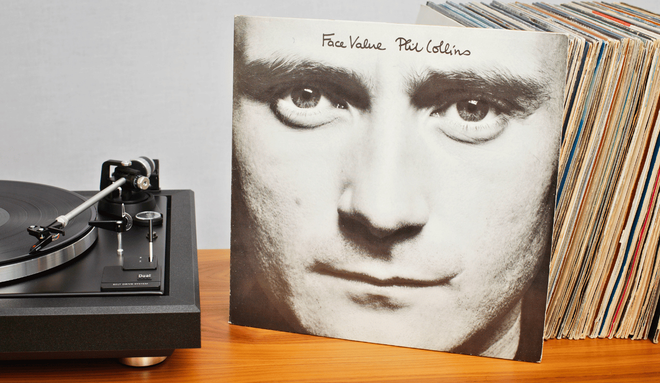 The vinyl album 'Face Value' is propped up on a shelf next to a turntable. 