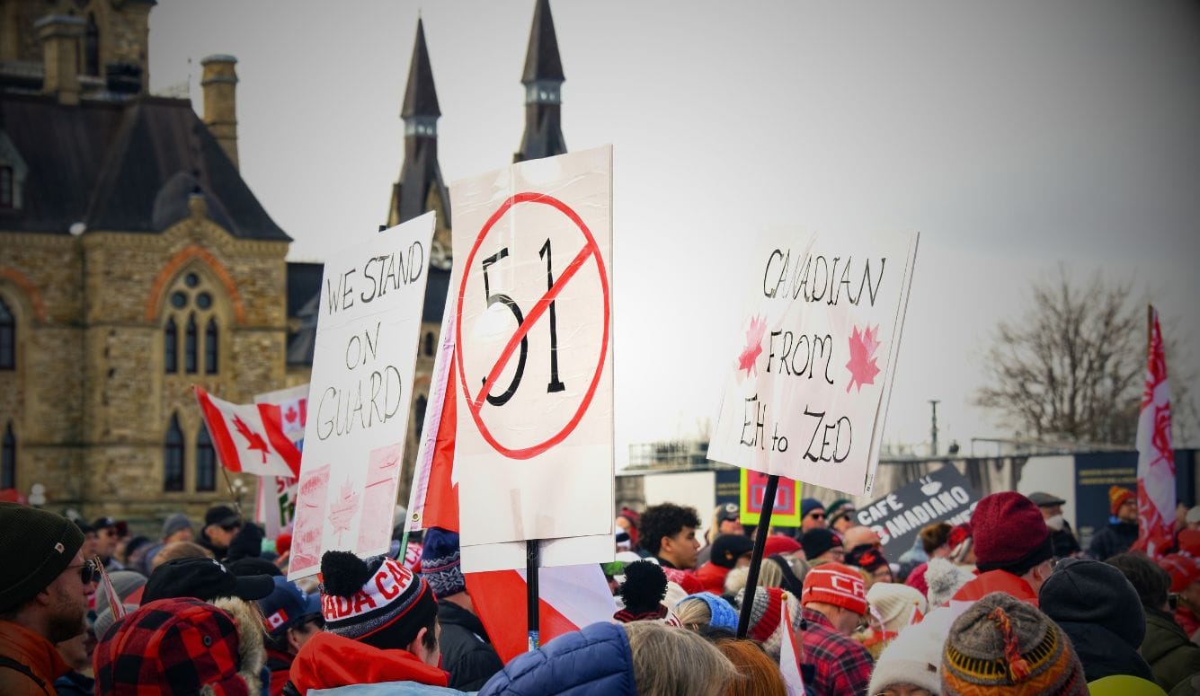 Ottawa rally with Canadian flags and signs opposing US tariffs and affirming Canadian sovereignty.
