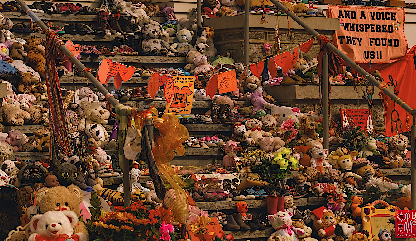 Memorial display of stuffed animals, flowers and handwritten signs on wooden steps in Brantford, Ontario