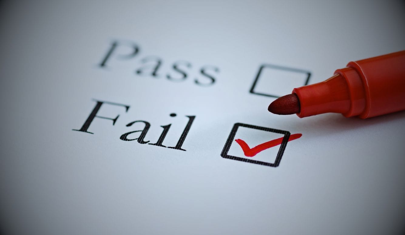Red marker pen beside a form with a red tick in the ‘Fail’ checkbox.