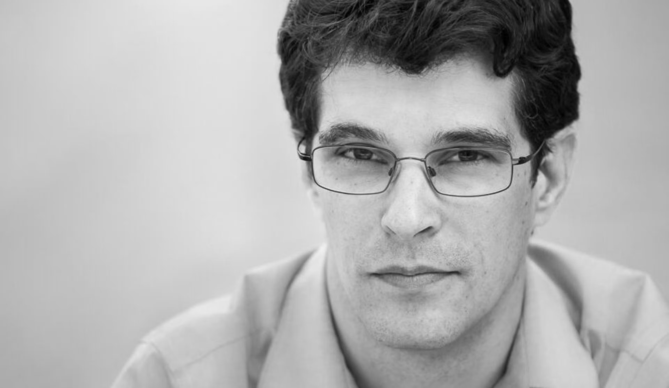 Steven Galloway, a man with dark hair and glasses, in a close-up black-and-white portrait.
