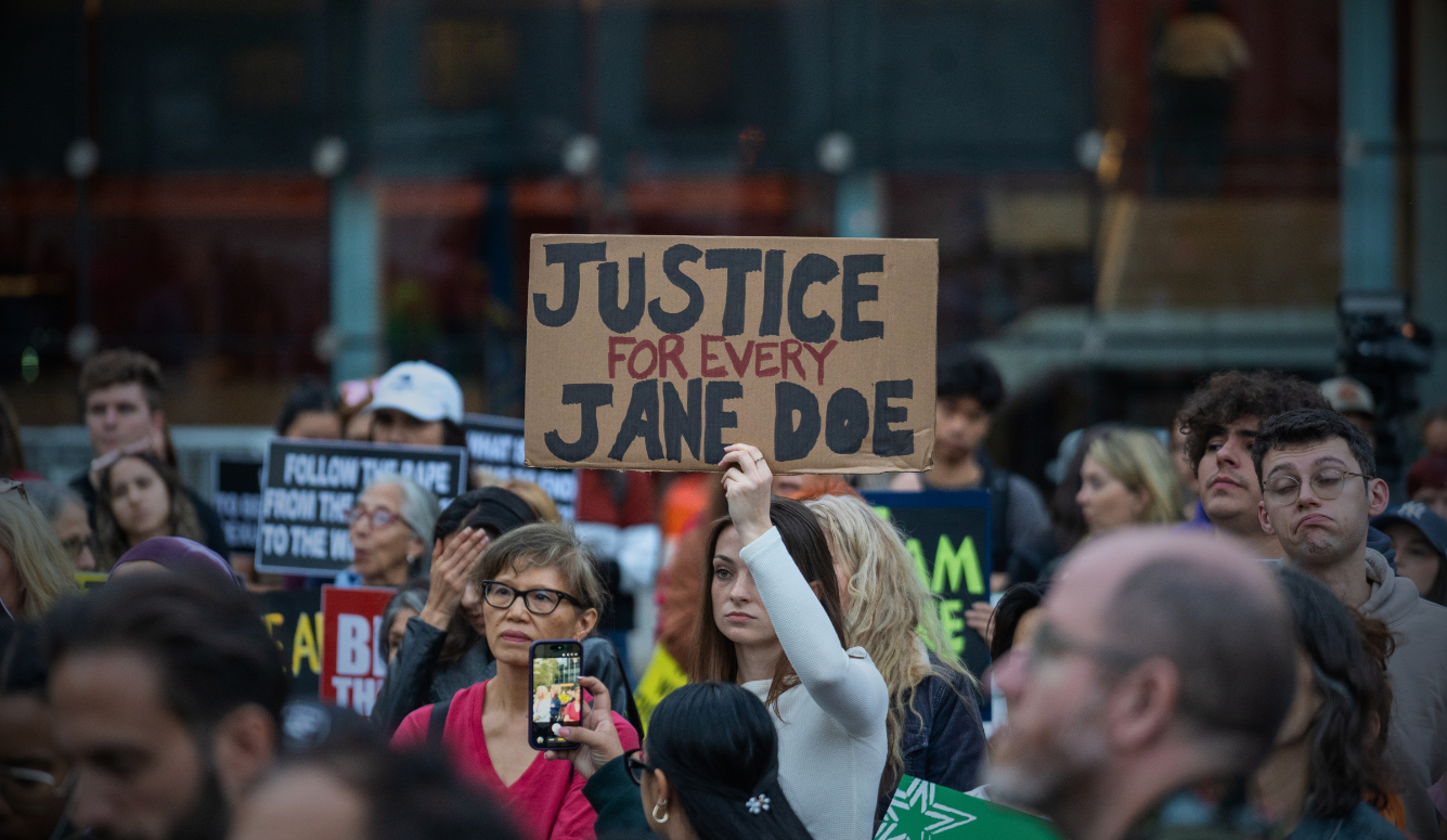 Women gather at Foley Square in New York City, holding signs calling for justice and accountability for sexual violence.
