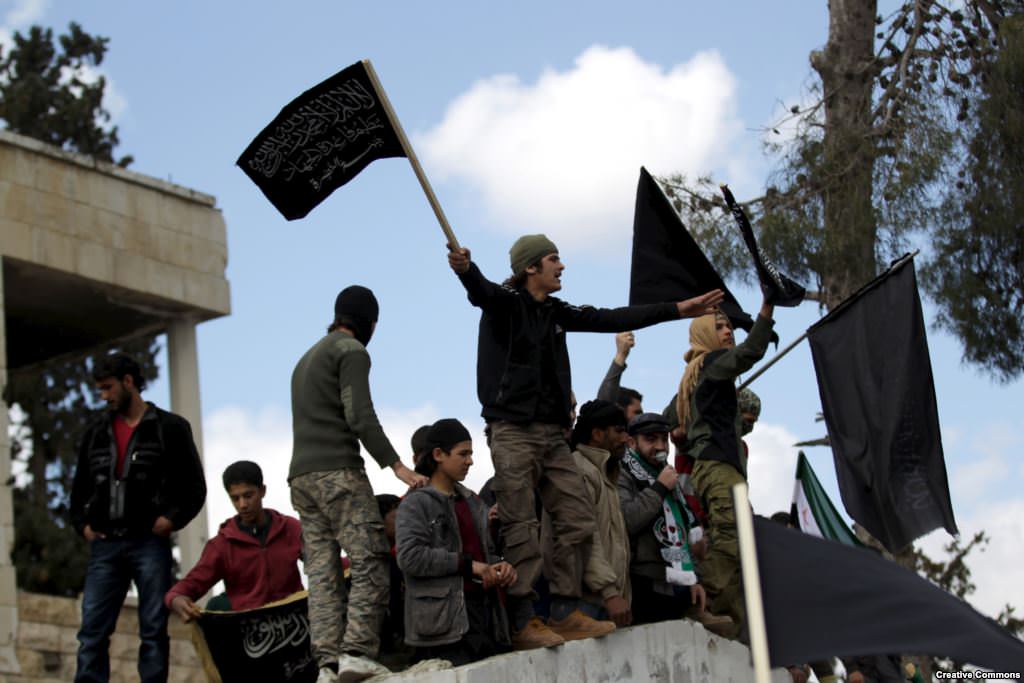 The al-Nusra Front pledged allegiance to al-Qaeda in 2013. Image of men waving black flag in Syria.