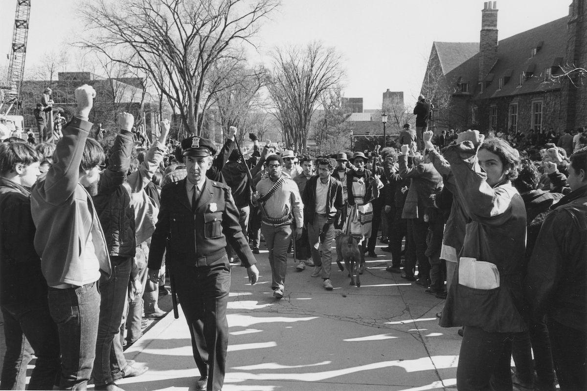 Protester Eric Evans (wearing bandolier) and other activists flanked by SDS students