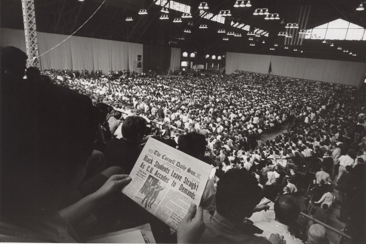 Person reading Daily Sun in the audience at Barton Hall.